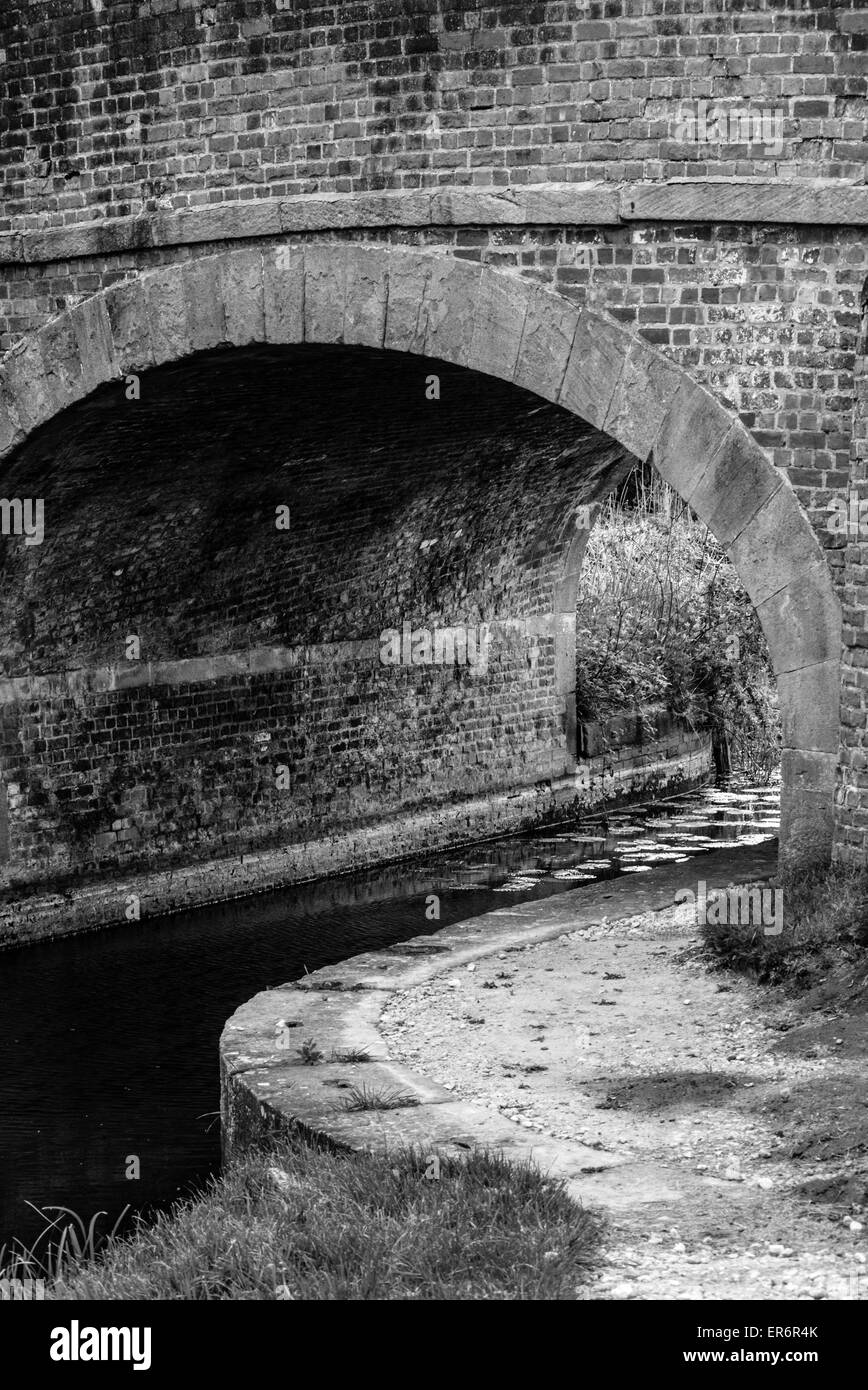 Immagine in bianco e nero, il canale che scorre sotto un ponte stradale Foto Stock