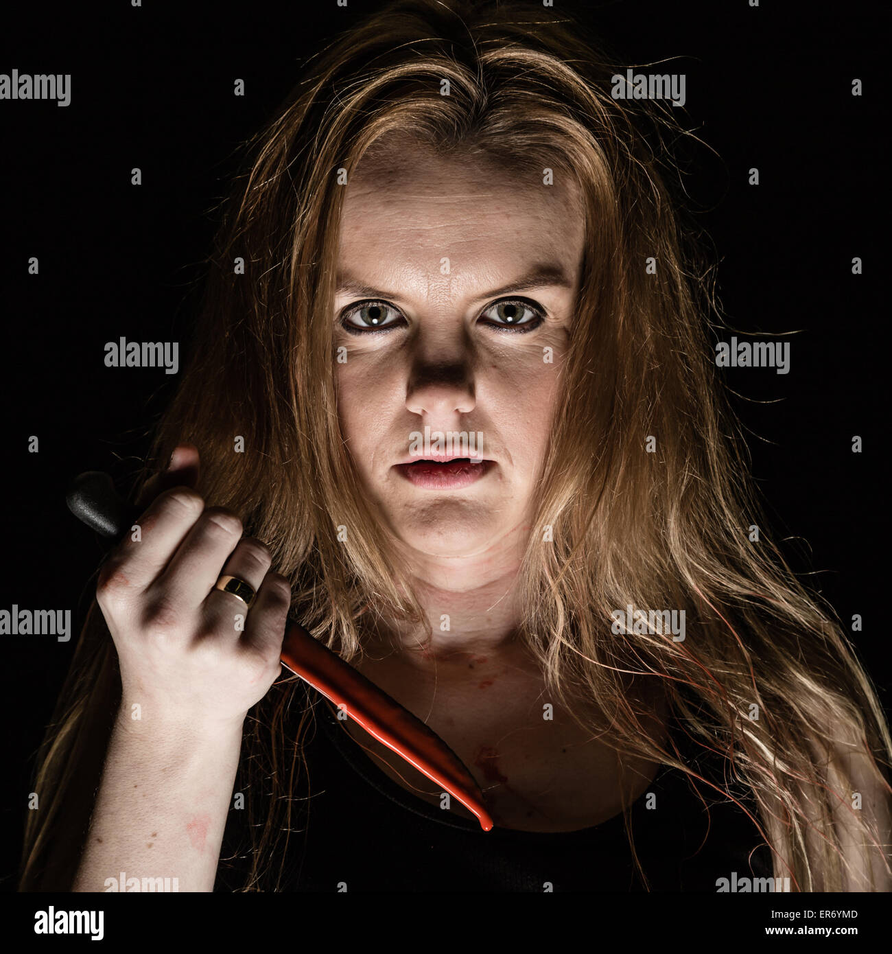 Una giovane donna tenendo un coltello insanguinato Foto Stock