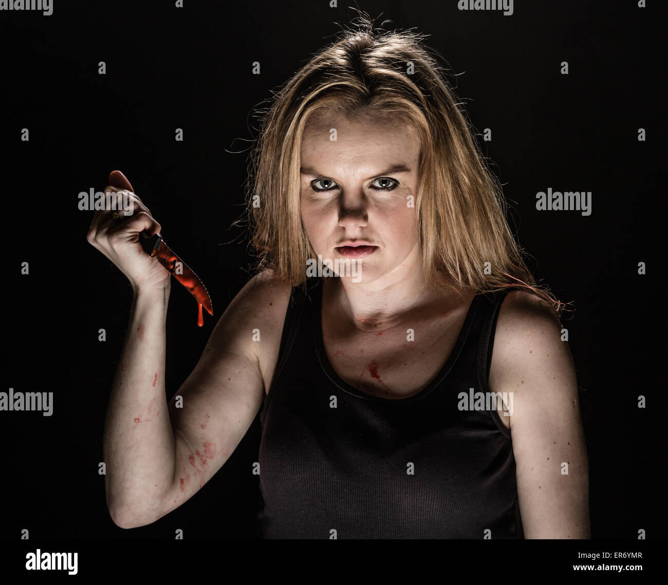 Una giovane donna tenendo un coltello insanguinato Foto Stock