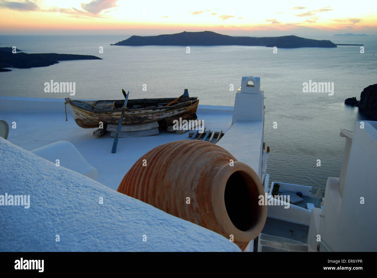 L'urna greca e la vecchia barca su un tetto bianco a Fira, Santorini, Grecia, con la caldera dietro. Foto Stock