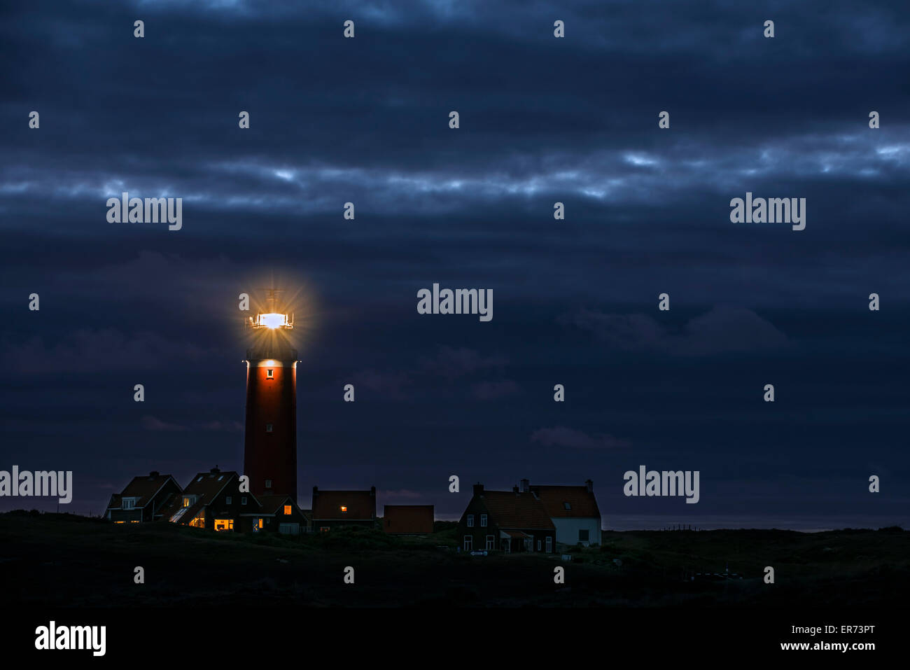 Eierland faro con la luce della lanterna lucenti oltre mare di Wadden durante la notte su isola olandese di Texel, Isole Frisone, Paesi Bassi Foto Stock
