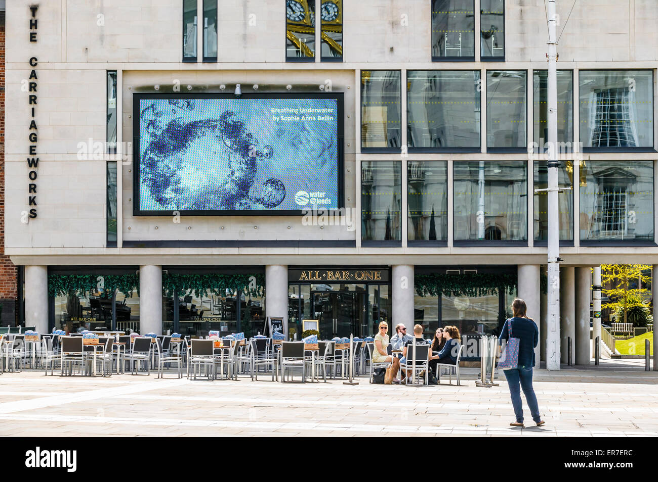 Il carrello funziona al di fuori di tutti i bar uno Millennium Square, gruppo di persone sedute intorno ad un tavolo Foto Stock