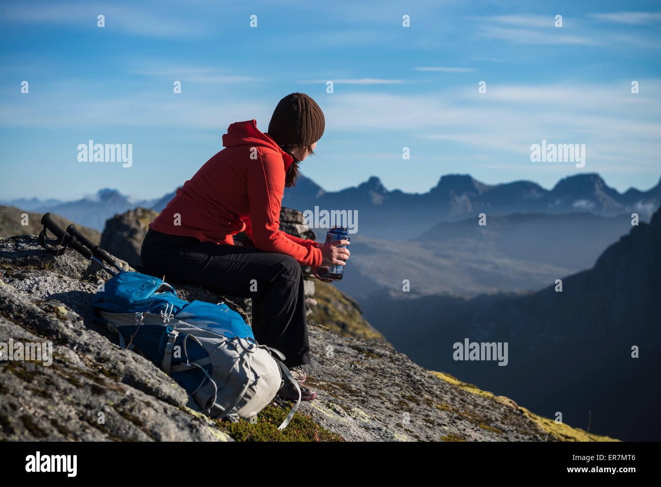 Escursionista femmina si prende una pausa e gode di viste sulla montagna, Moskenesøy, Isole Lofoten in Norvegia Foto Stock