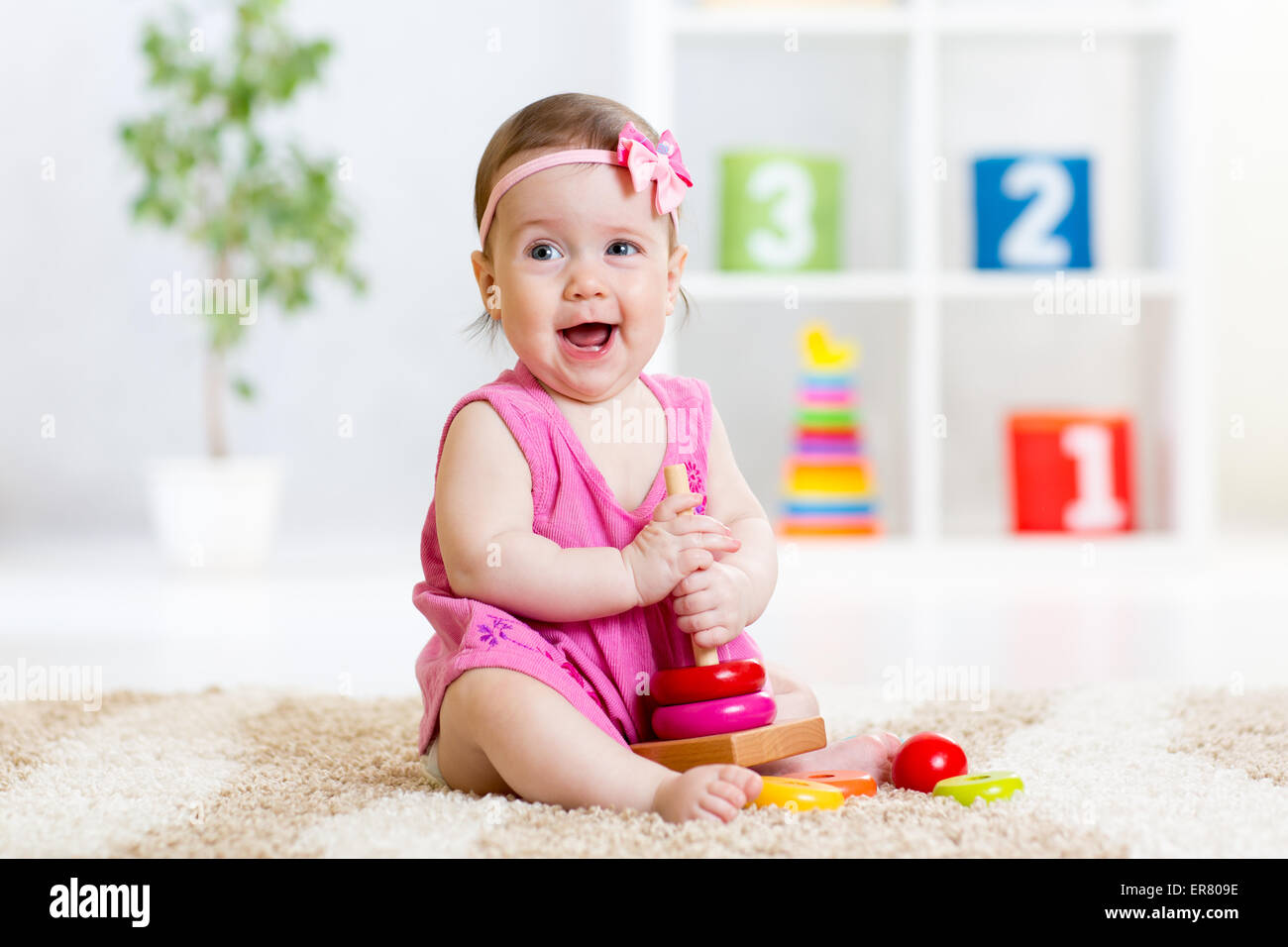 Carino baby giocando con colorate piramide giocattolo a casa Foto Stock