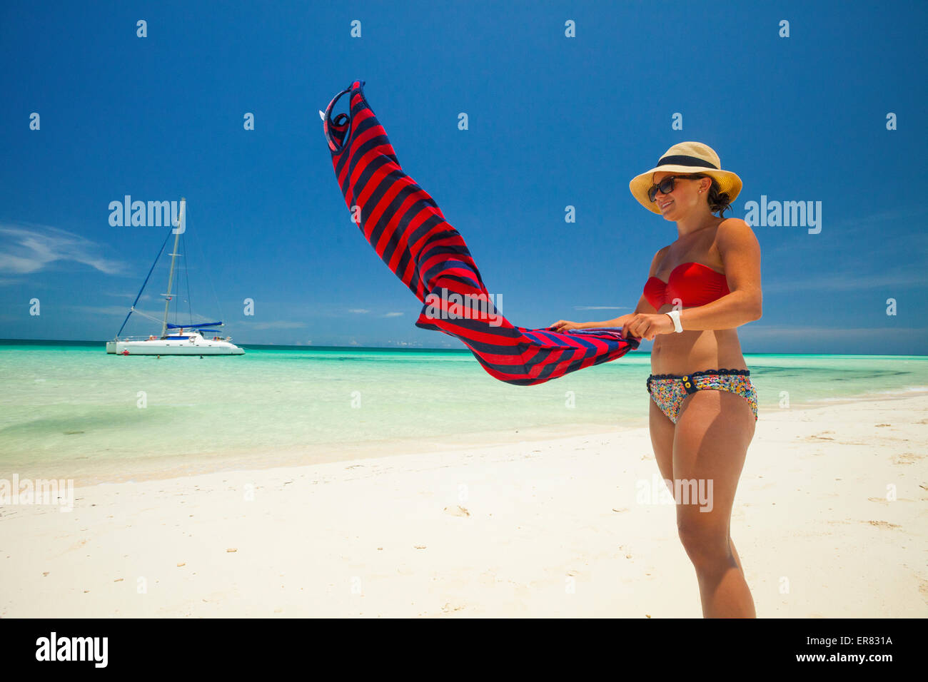 Una giovane donna scuote la sabbia fuori dai suoi abiti estivi mentre godendo di una splendida spiaggia a Cuba. Foto Stock