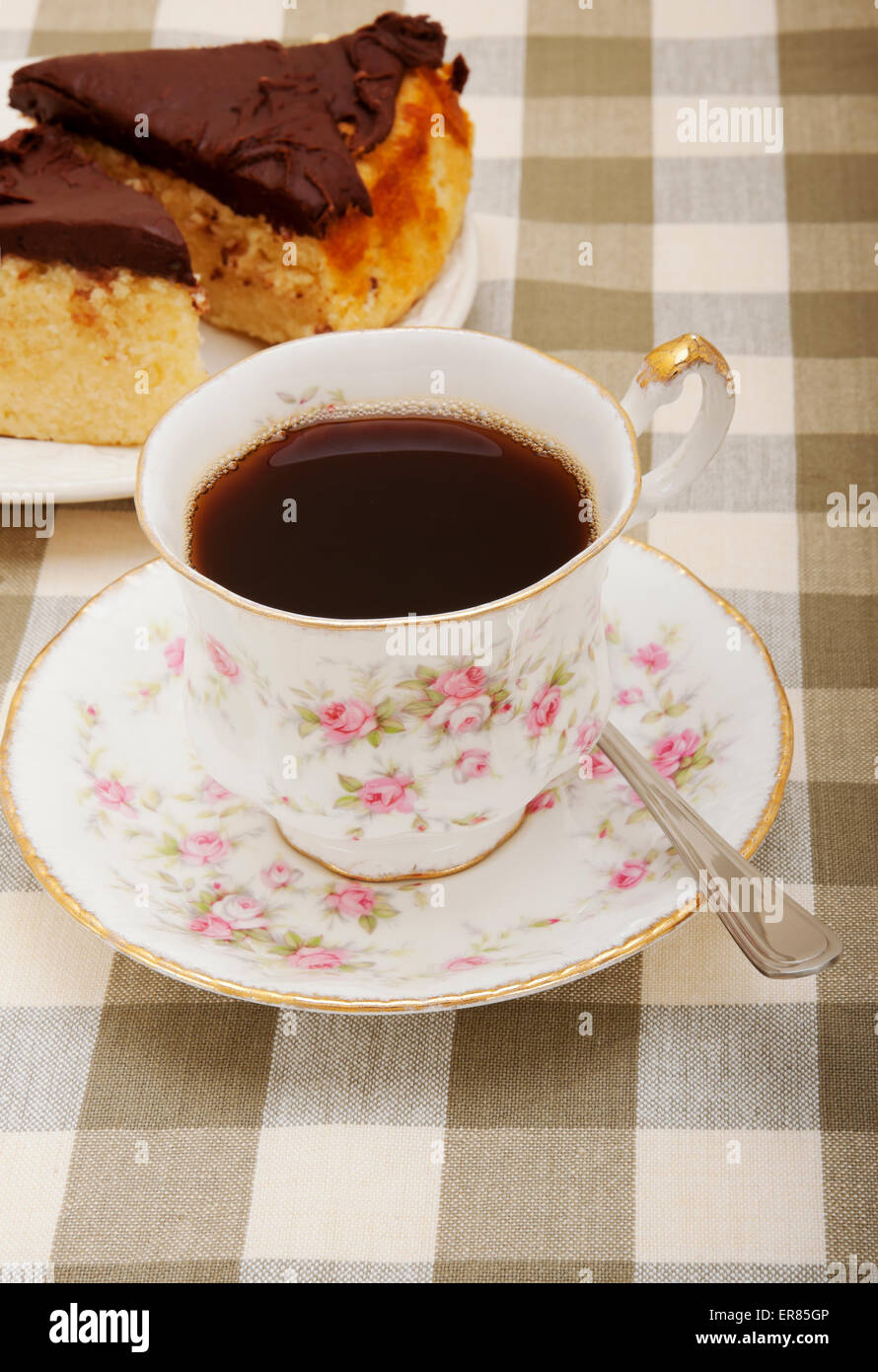 Primo piano di una tazza d'annata di porcellana e un piattino di tè al caffè nero e fette di torta al cioccolato Foto Stock