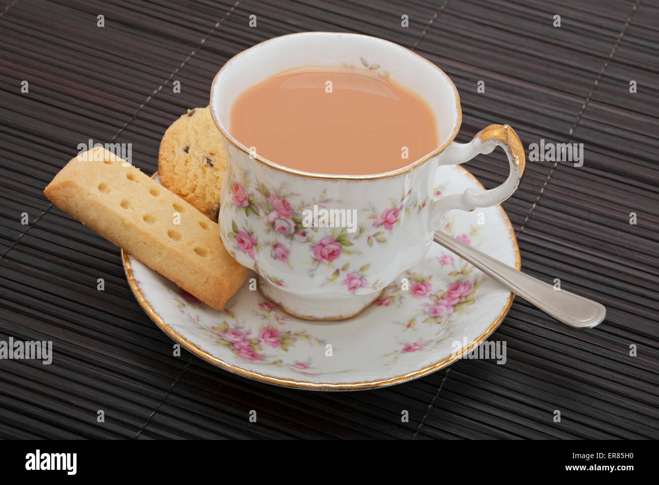 Primo piano di una tazza di tè con latte e biscotti frollini Foto Stock