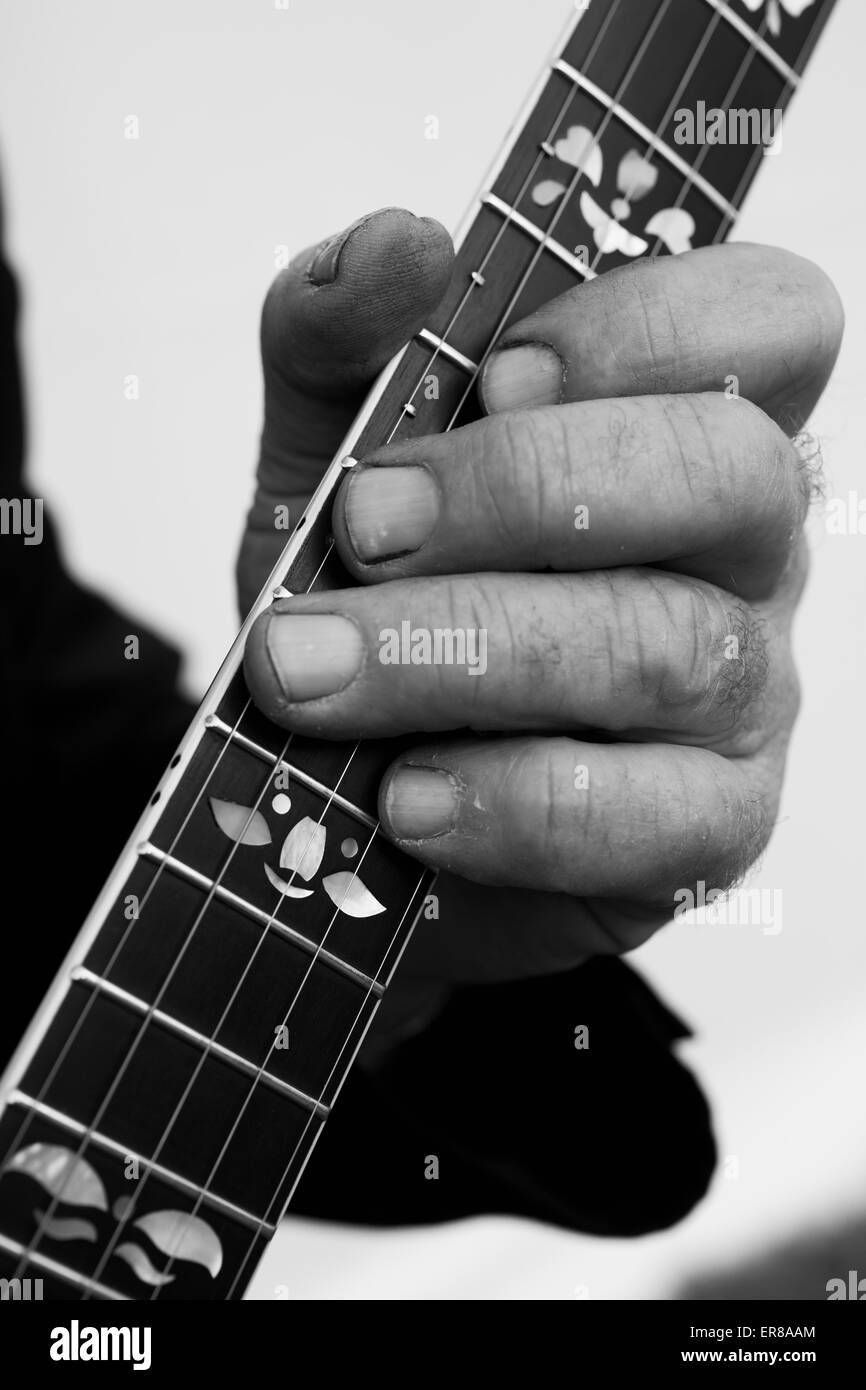 Immagine ritagliata di mano a suonare la chitarra contro uno sfondo grigio Foto Stock