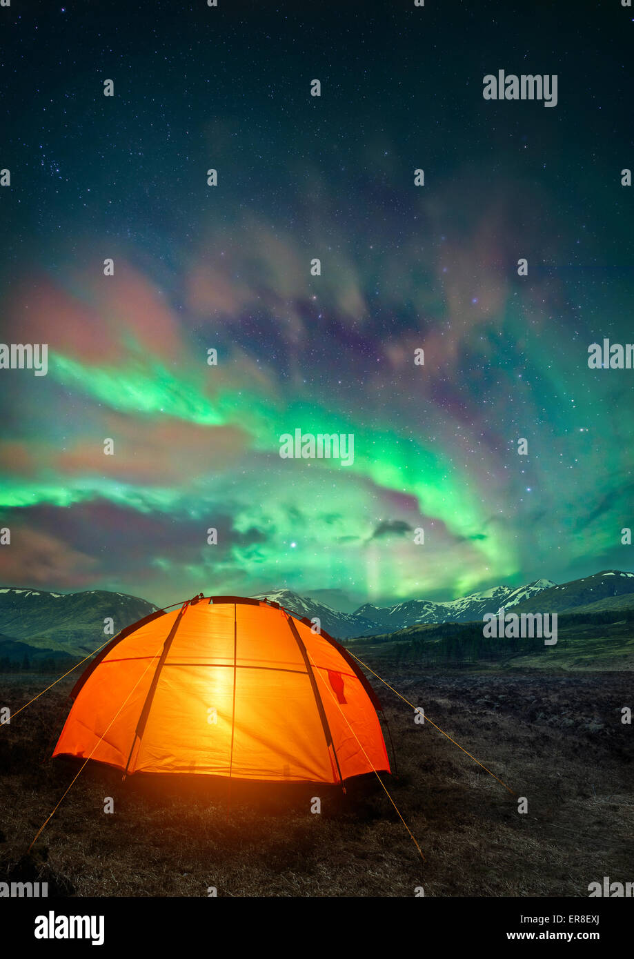 Una tenda da campeggio incandescente sotto le luci del nord. Notte tempo camping scena. Foto Stock