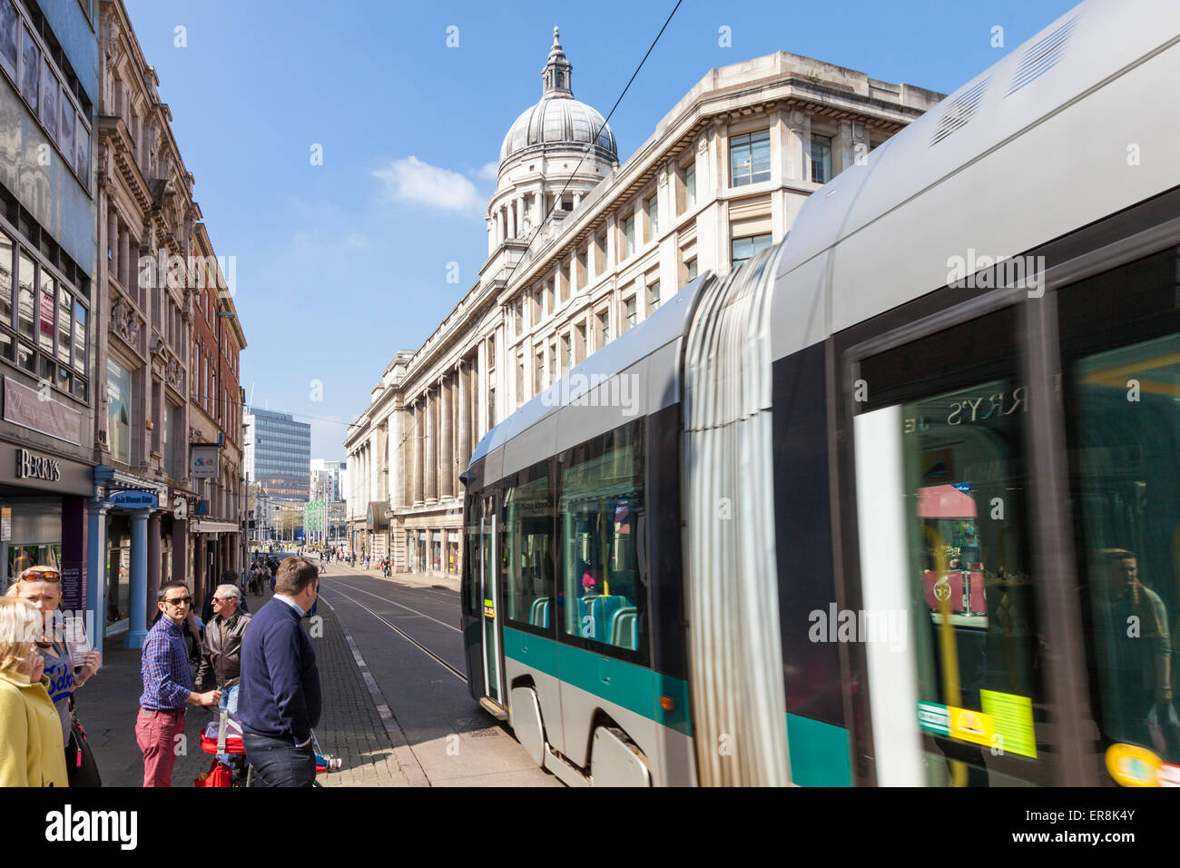 Le persone in attesa di attraversare la strada come un tram passa da. Nottingham, Inghilterra, Regno Unito Foto Stock