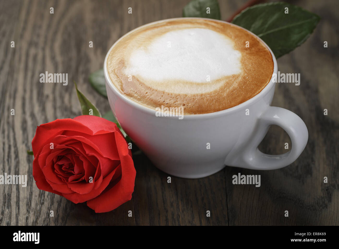 Cappuccino fresco con una rosa rossa sul tavolo Foto Stock