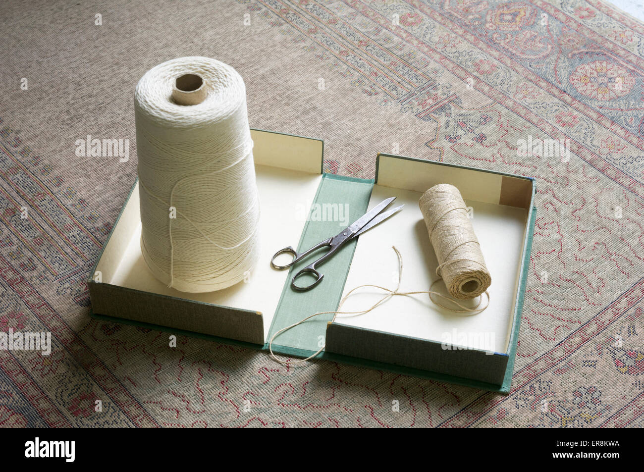 Bobine di filo e un paio di forbici nella casella su rug Foto Stock
