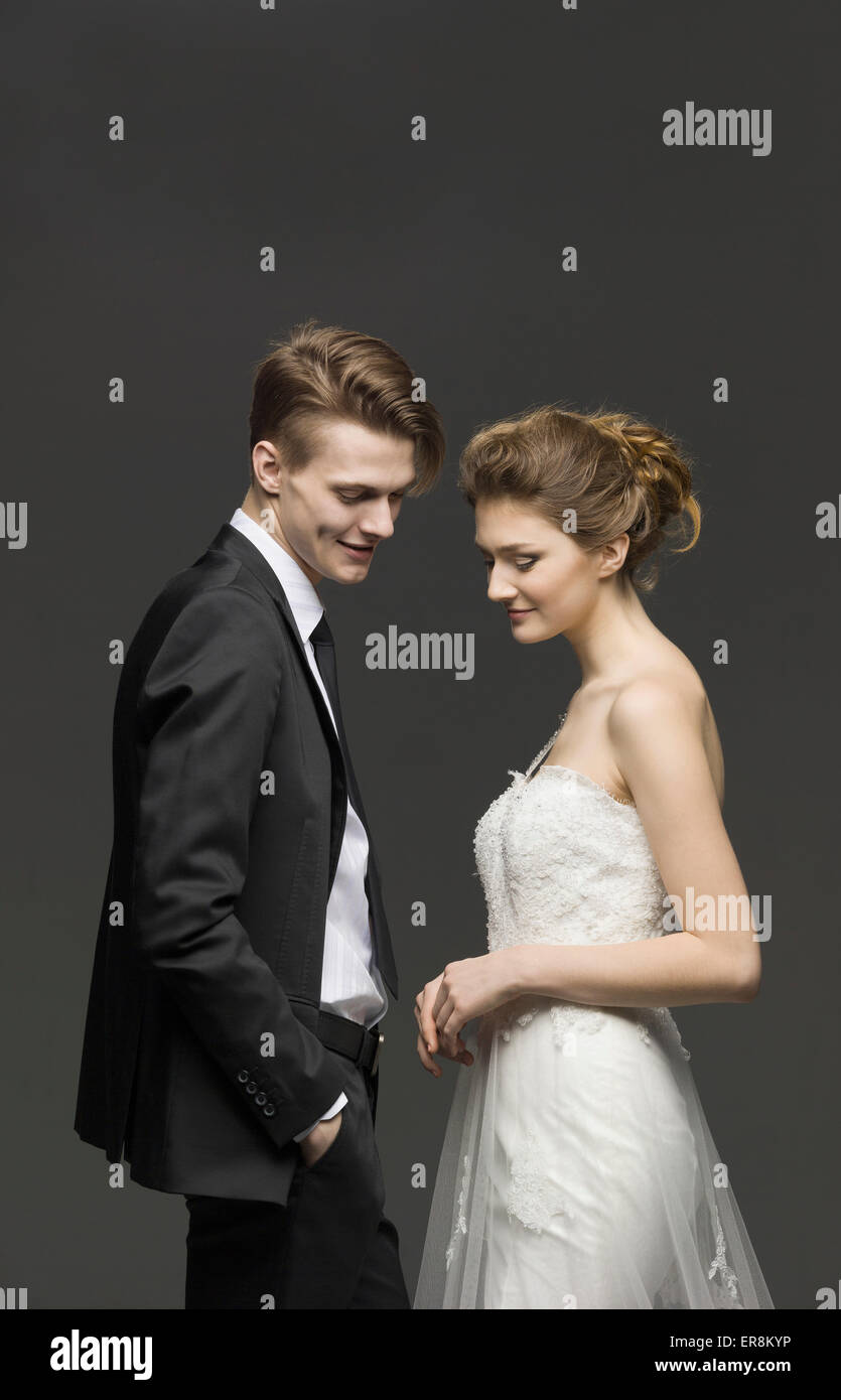 Vista laterale della coppia di novelli sposi su sfondo grigio Foto Stock