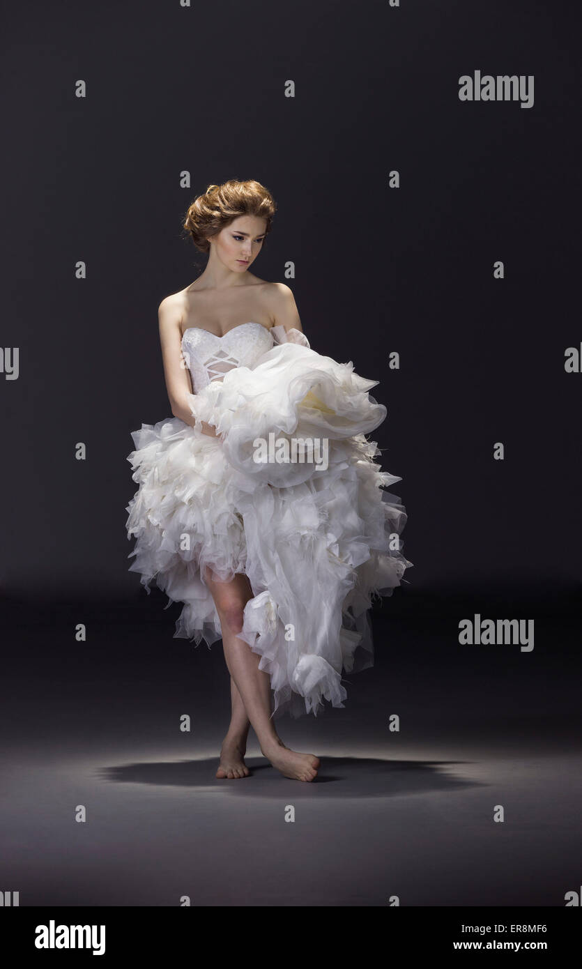 Per tutta la lunghezza della giovane sposa in abito da sposa in piedi su sfondo colorato Foto Stock