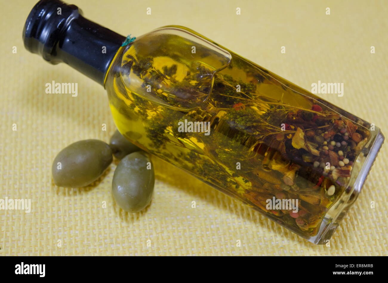 Olio di oliva Bottiglia con erbe aromatiche interno decorato con freschi olive verdi Foto Stock