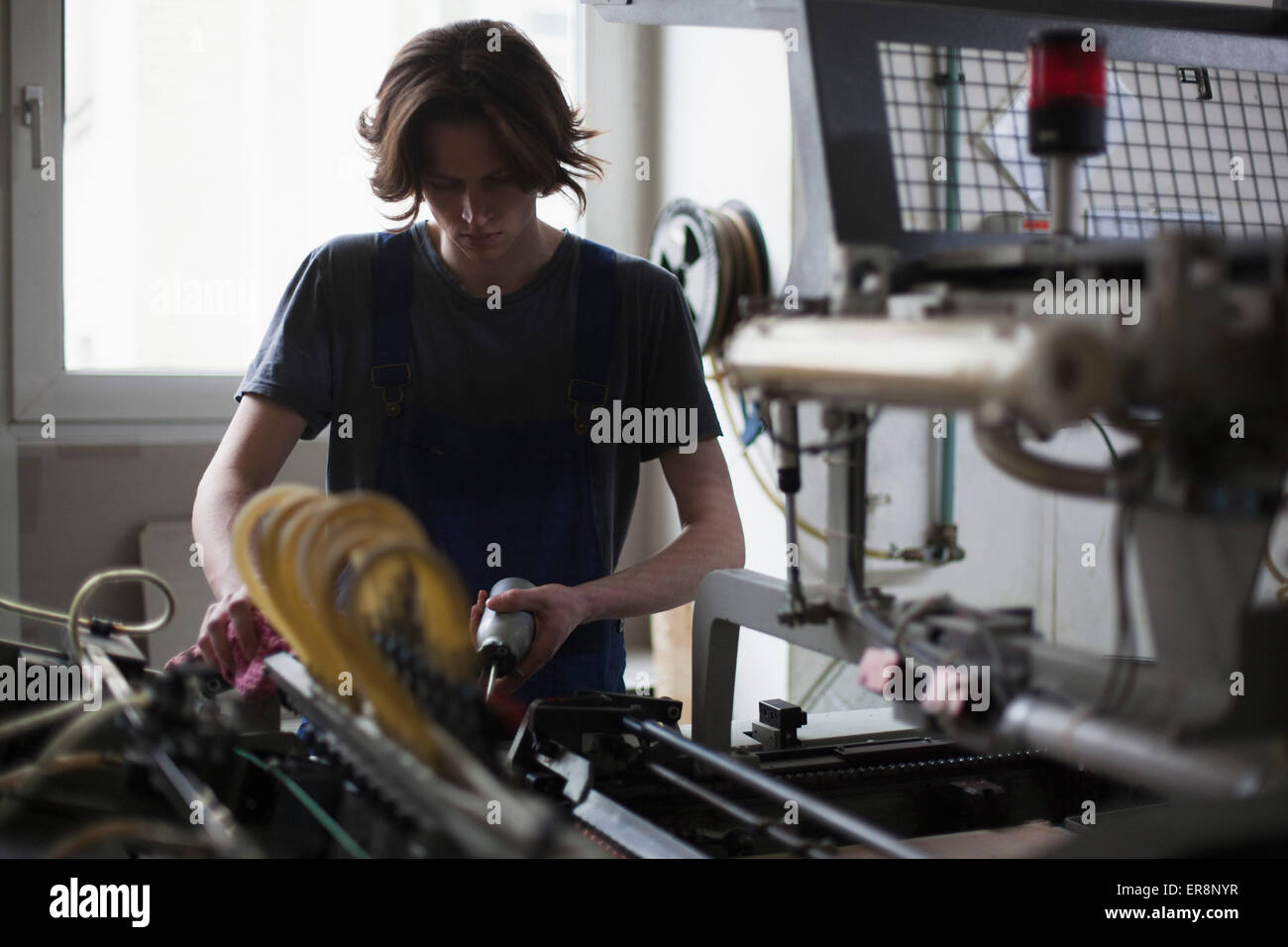 Giovane lavoratore manuale macchina di lubrificazione in fabbrica Foto Stock