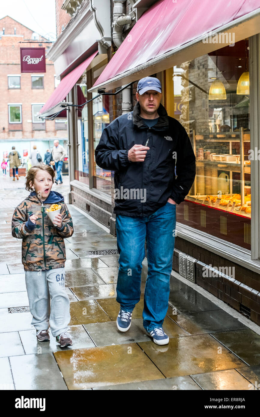 Padre e figlio a piedi sotto la pioggia in Salisbury Foto Stock