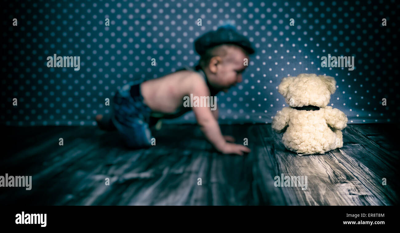 Bambino con cappello vintage e giarrettiere gioca con Teddy bear Foto Stock
