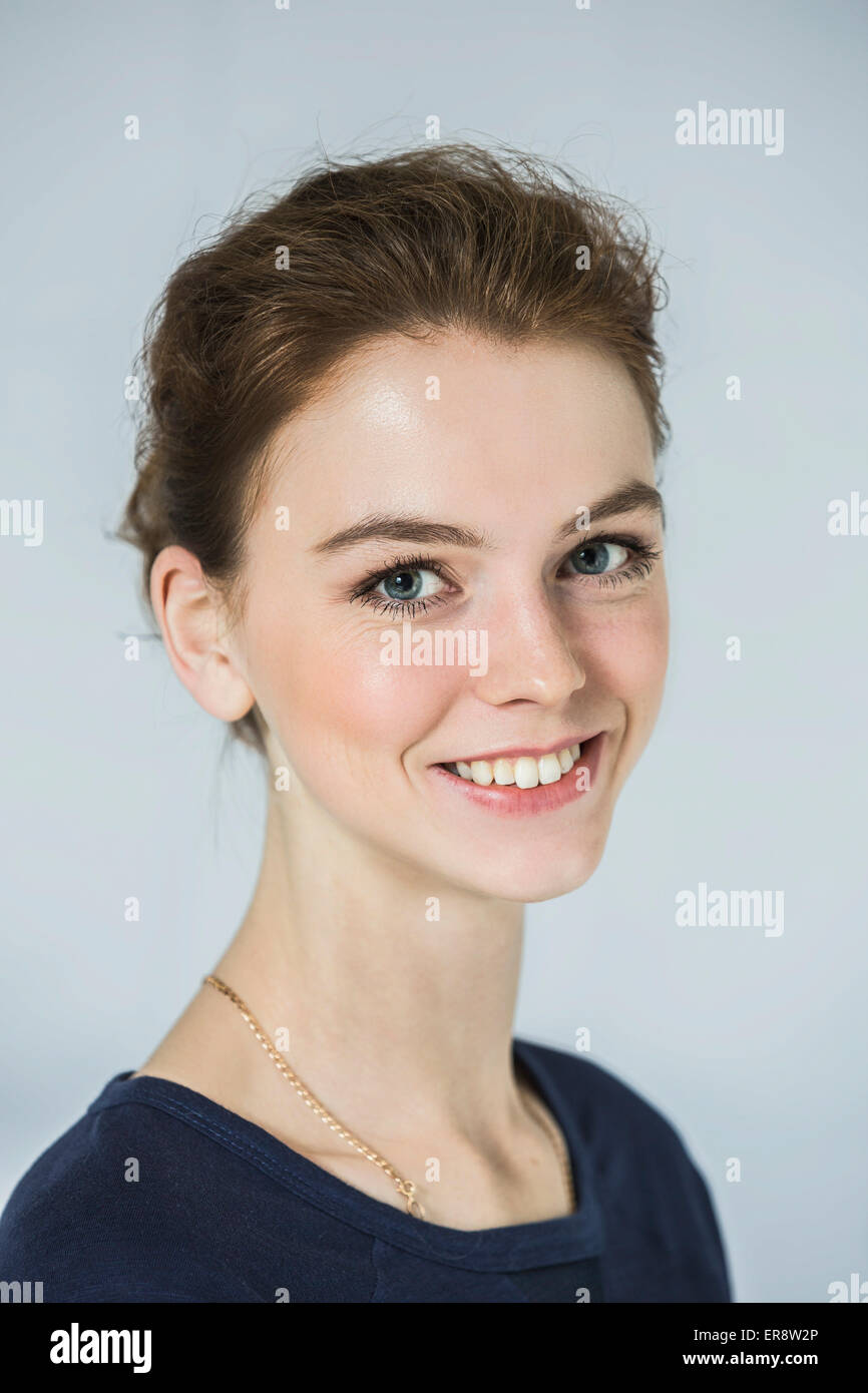 Close-up verticale di felice bella donna contro uno sfondo grigio Foto Stock