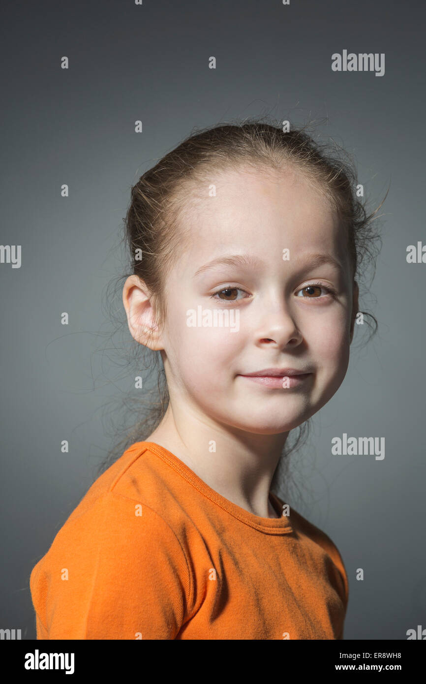 Ritratto di ragazza sorridente contro uno sfondo grigio Foto Stock