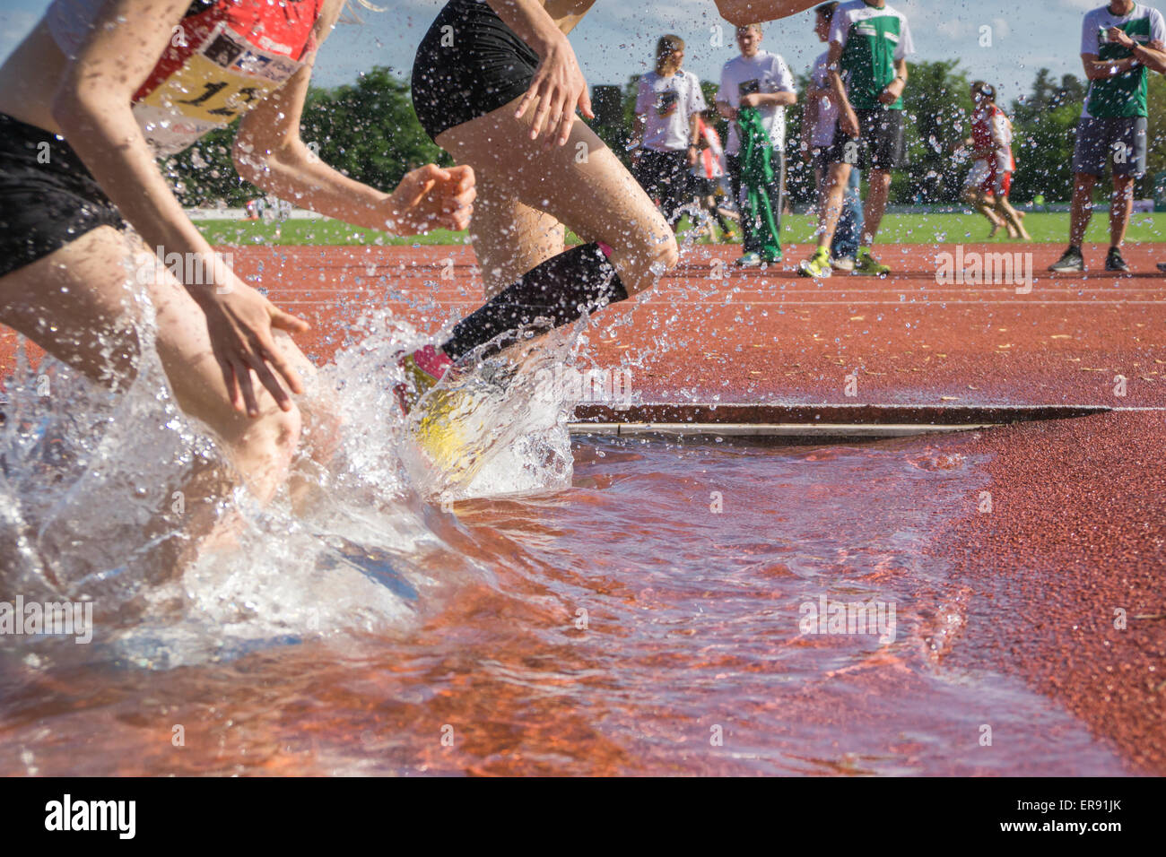 PLIEZHAUSEN, BADEN-WUERTTEMBERG/ Germania - Mai 17 2015: Sconosciuto steeplechasers femmina in tedesco Track & Field Championships in esecuzione attraverso l'acqua ostacolo Foto Stock