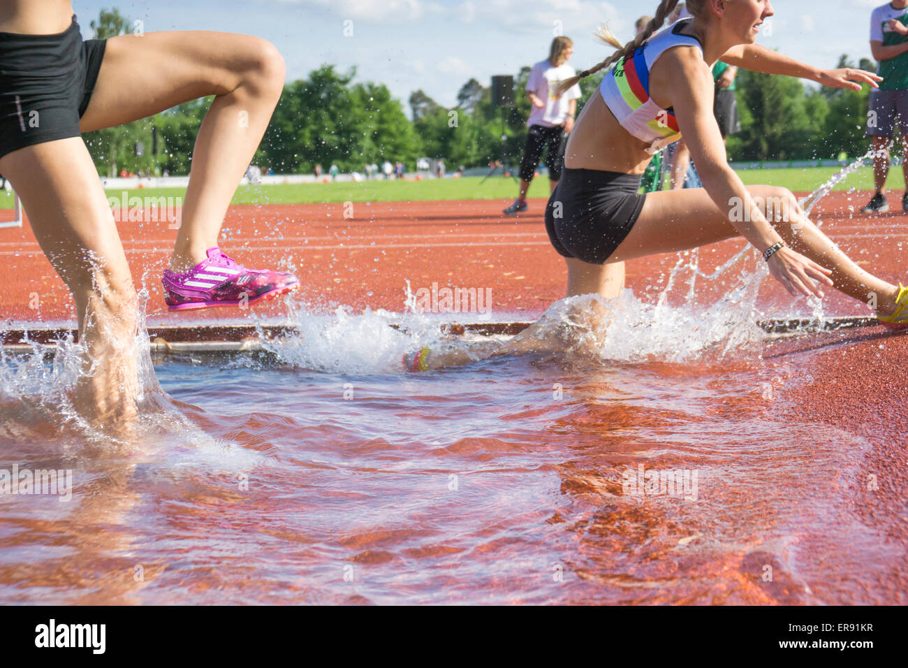 PLIEZHAUSEN, BADEN-WUERTTEMBERG/ Germania - Mai 17 2015: Sconosciuto steeplechasers femmina in tedesco Track & Field Championships in esecuzione attraverso l'acqua ostacolo Foto Stock