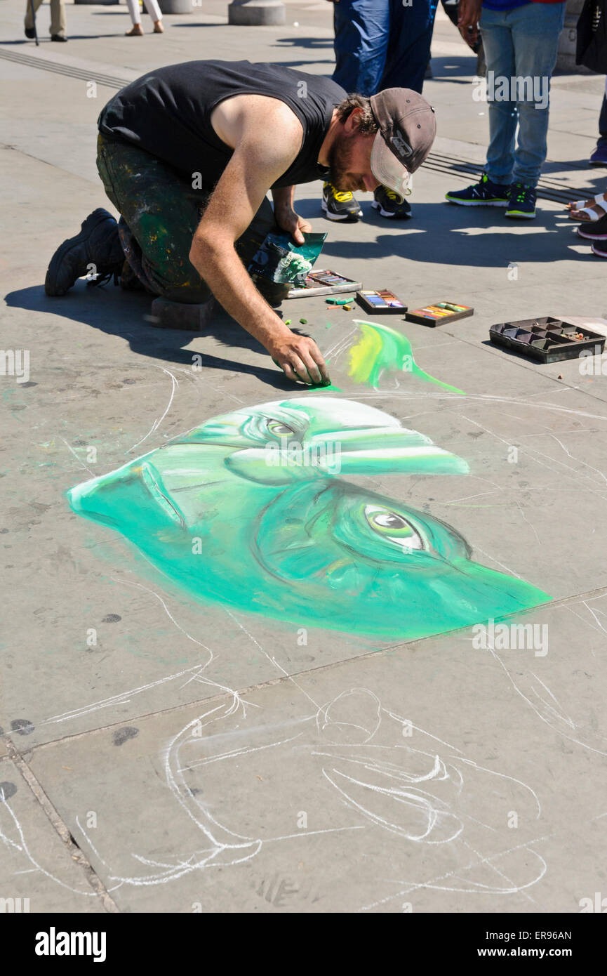 Un artista maschile di disegno di un denaro il volto sul pavimento con le matite colorate, Londra, Inghilterra, Regno Unito. Foto Stock