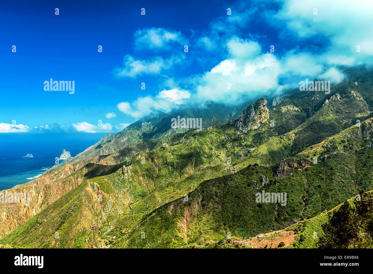 Nuvole e montagne verdi o rocce con cielo blu sullo sfondo vicino all'Oceano Atlantico paesaggio di Tenerife Isole Canarie, Spagna Foto Stock