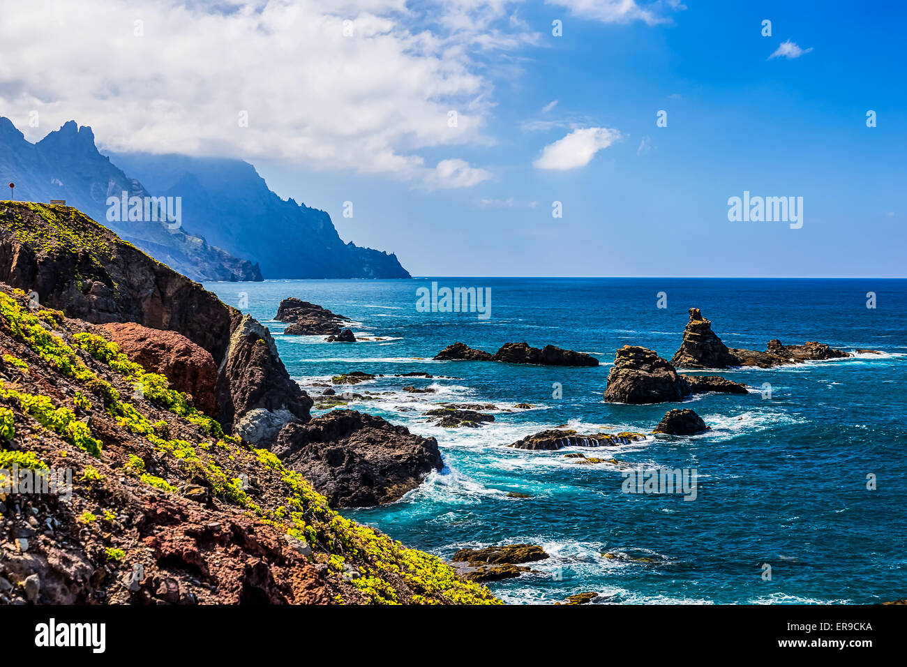 Costa o riva dell Oceano Atlantico con verde di montagna o di roccia e cielo blu con nuvole e skyline o horizon in Tenerife Canarie Foto Stock