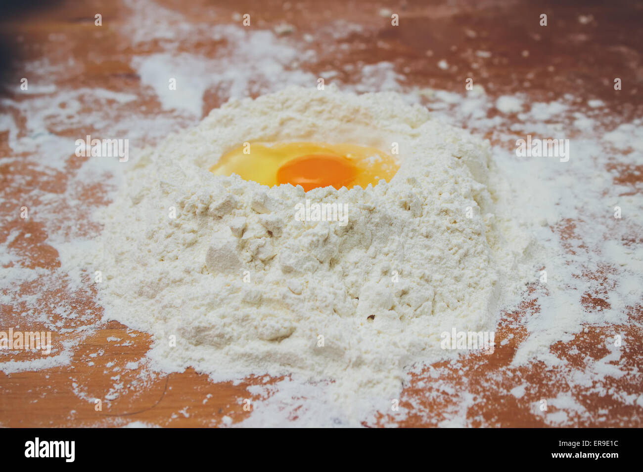La produzione di pane, la miscelazione degli ingredienti alimentari: tuorlo d'uovo su un fiocco di farina closeup. Colori retrò Foto Stock