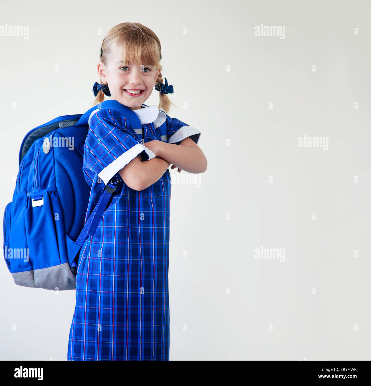 Bambina vestito nella sua uniforme scolastica e zaino pronto ad andare a scuola Foto Stock