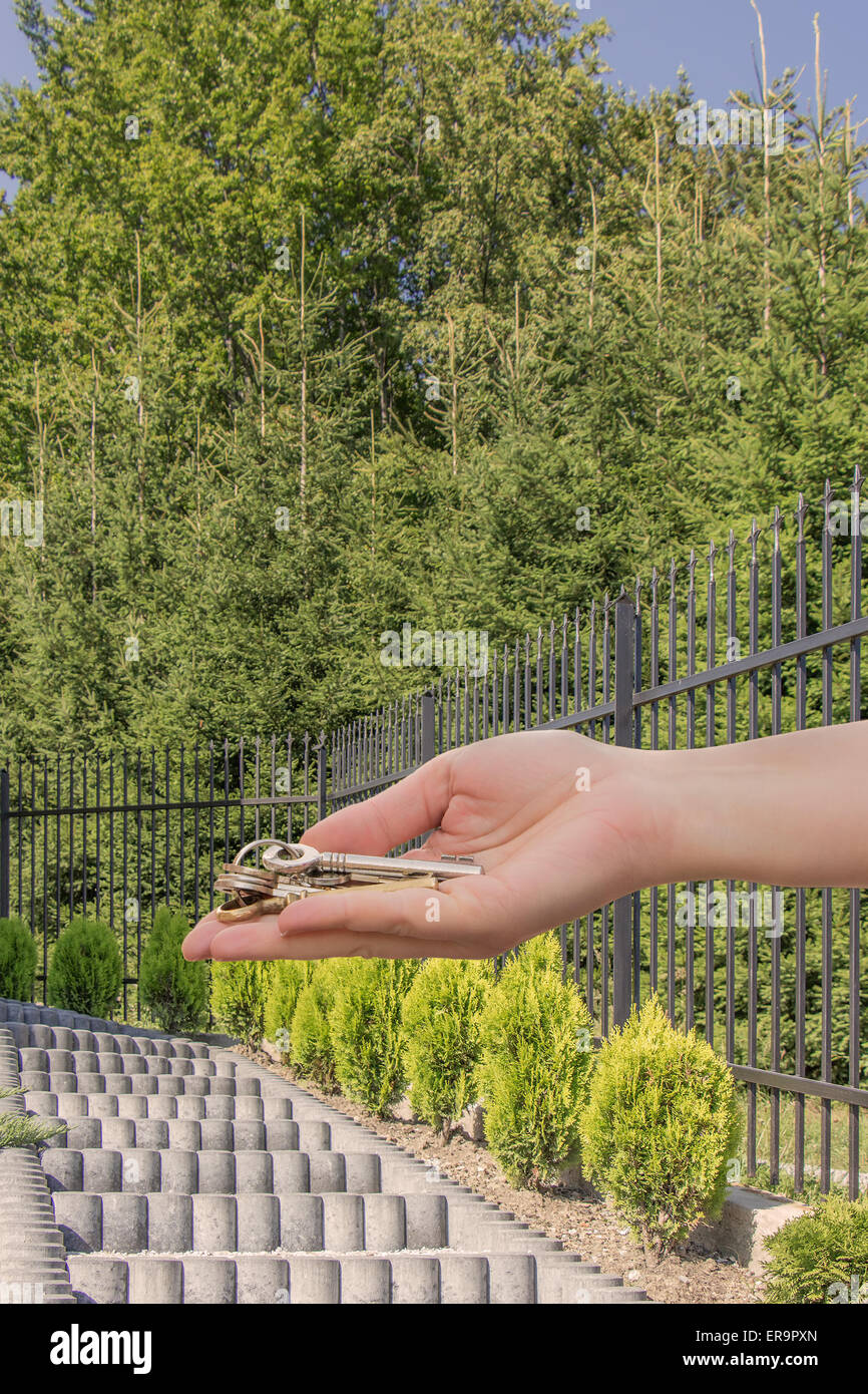 Donna mano che offre tasti nella parte anteriore dei gradini di una casa. Concetto di futuro ottimista. Foto Stock