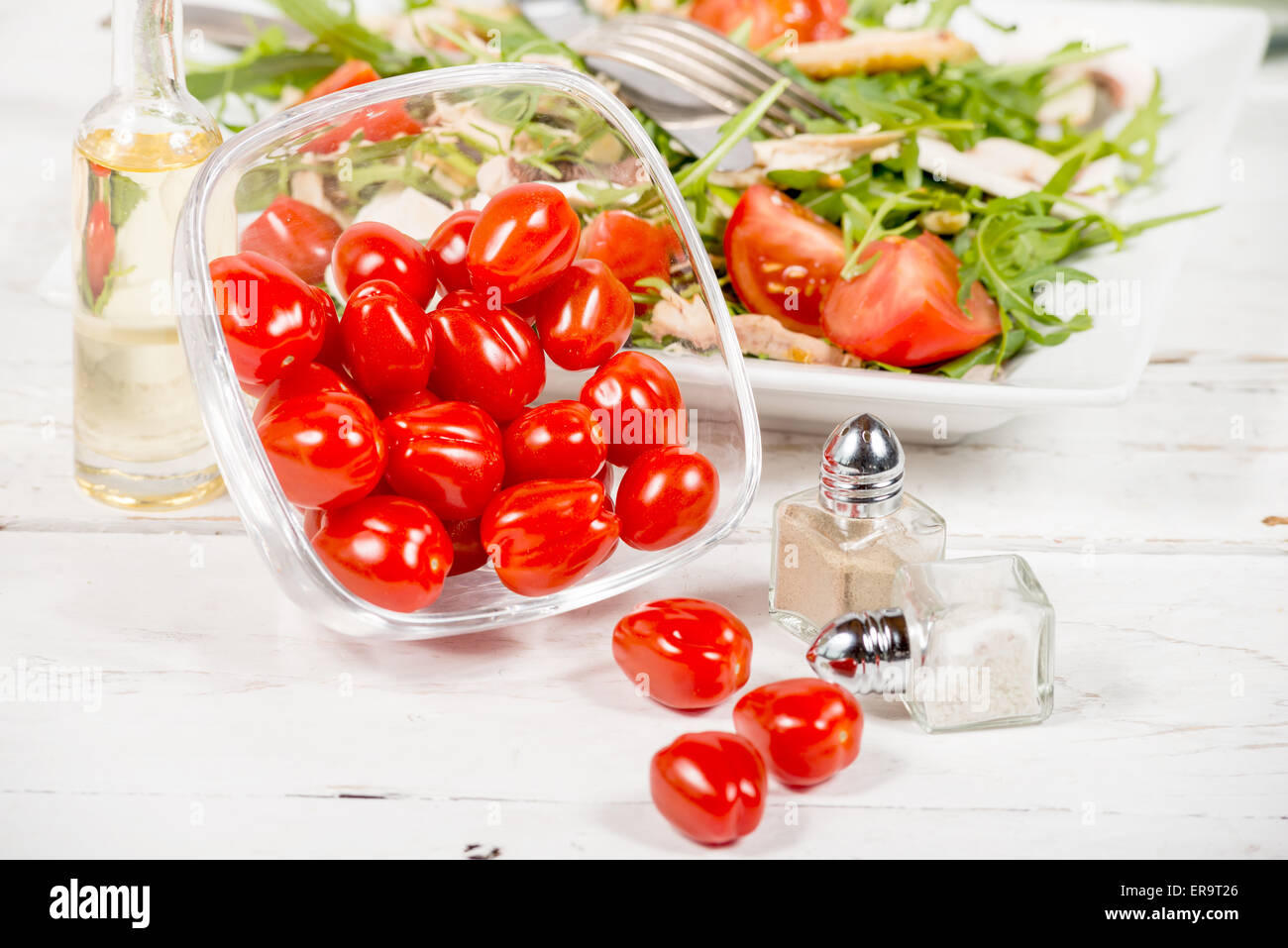 Piccoli pomodori in un vasetto di vetro con insalata di stagione Foto Stock