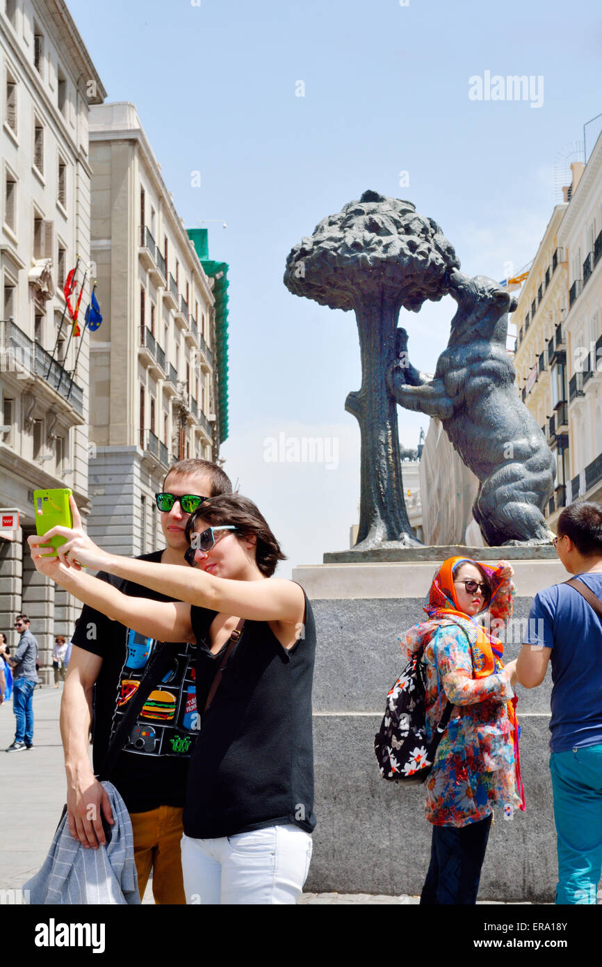 I turisti tenendo "selfie" foto nella parte anteriore di Orso e la (El Madroño) Tree o "orso e Corbezzolo" un simbolo di Madrid Foto Stock