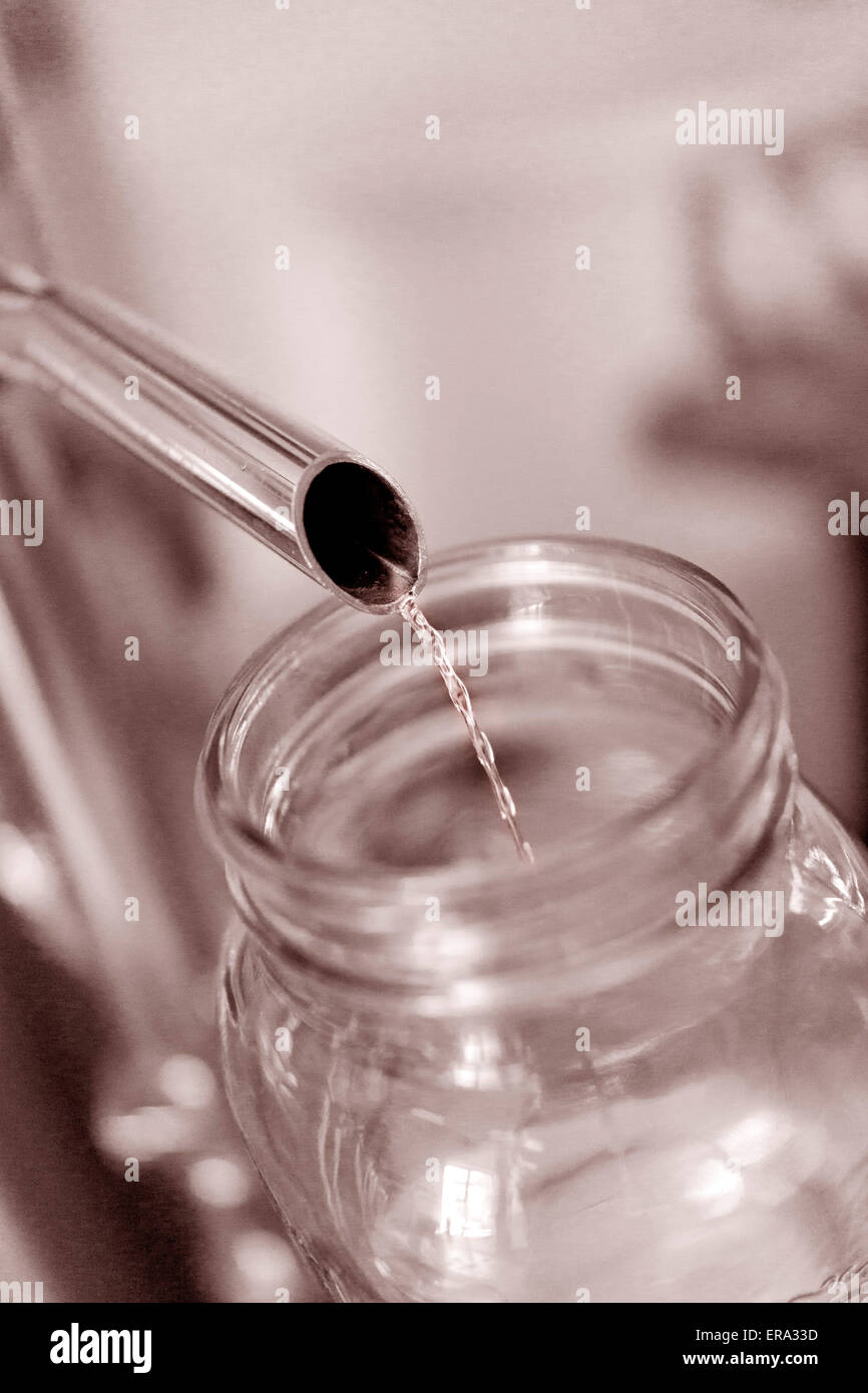 L'alcol versando in vaso di prova alla distilleria artigianale. Verticale colore seppia fotografia a Key West distillando, Florida, Stati Uniti d'America Foto Stock