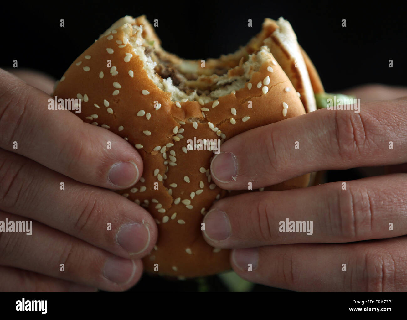 Un uomo mangia un Big Mac burger in corrispondenza di un ramo di un ristorante fast food in franchising McDonalds a Colonia, Germania, 25 maggio 2015. Foto: Oliver Berg/dpa Foto Stock