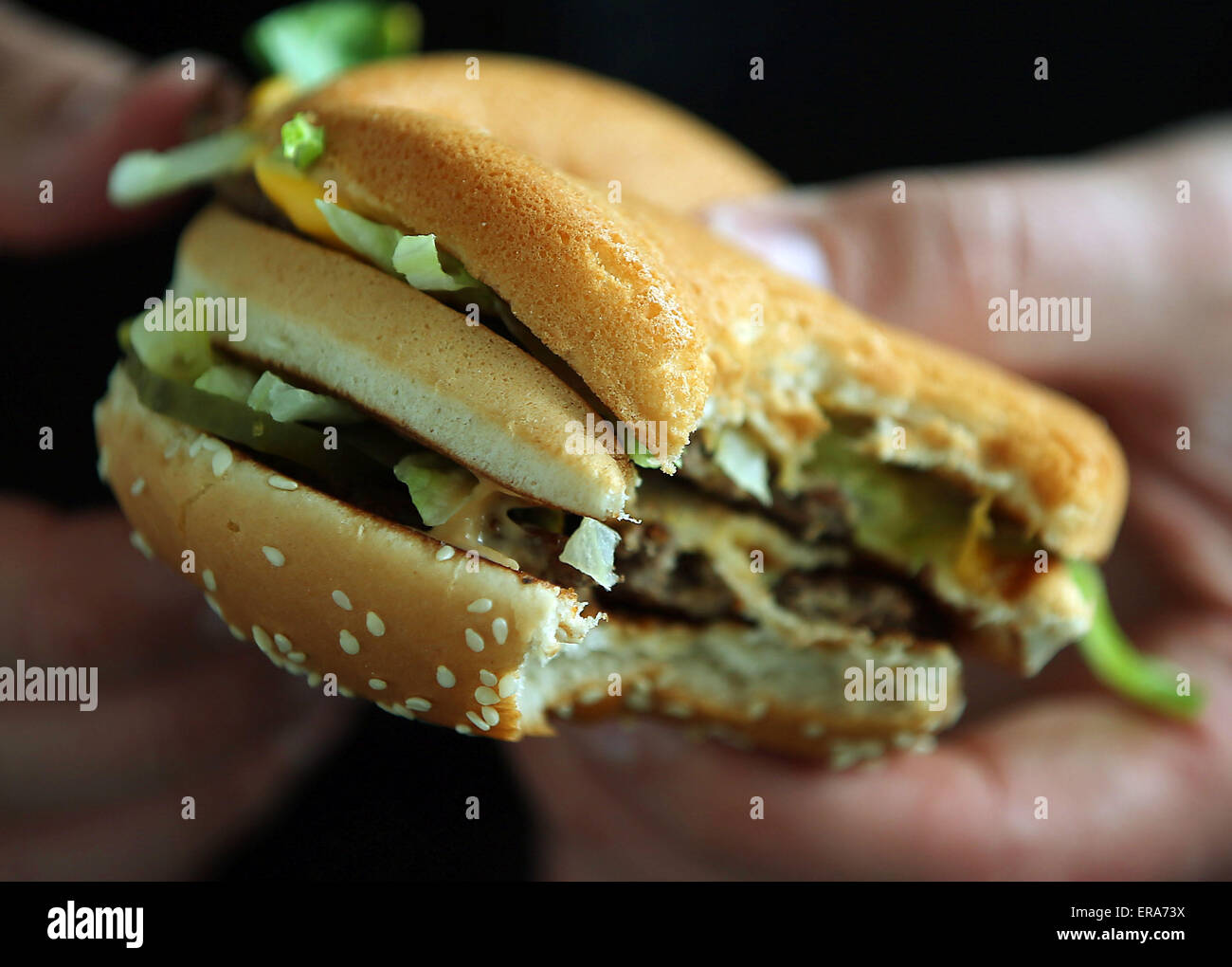 Un uomo mangia un Big Mac burger in corrispondenza di un ramo di un ristorante fast food in franchising McDonalds a Colonia, Germania, 25 maggio 2015. Foto: Oliver Berg/dpa Foto Stock