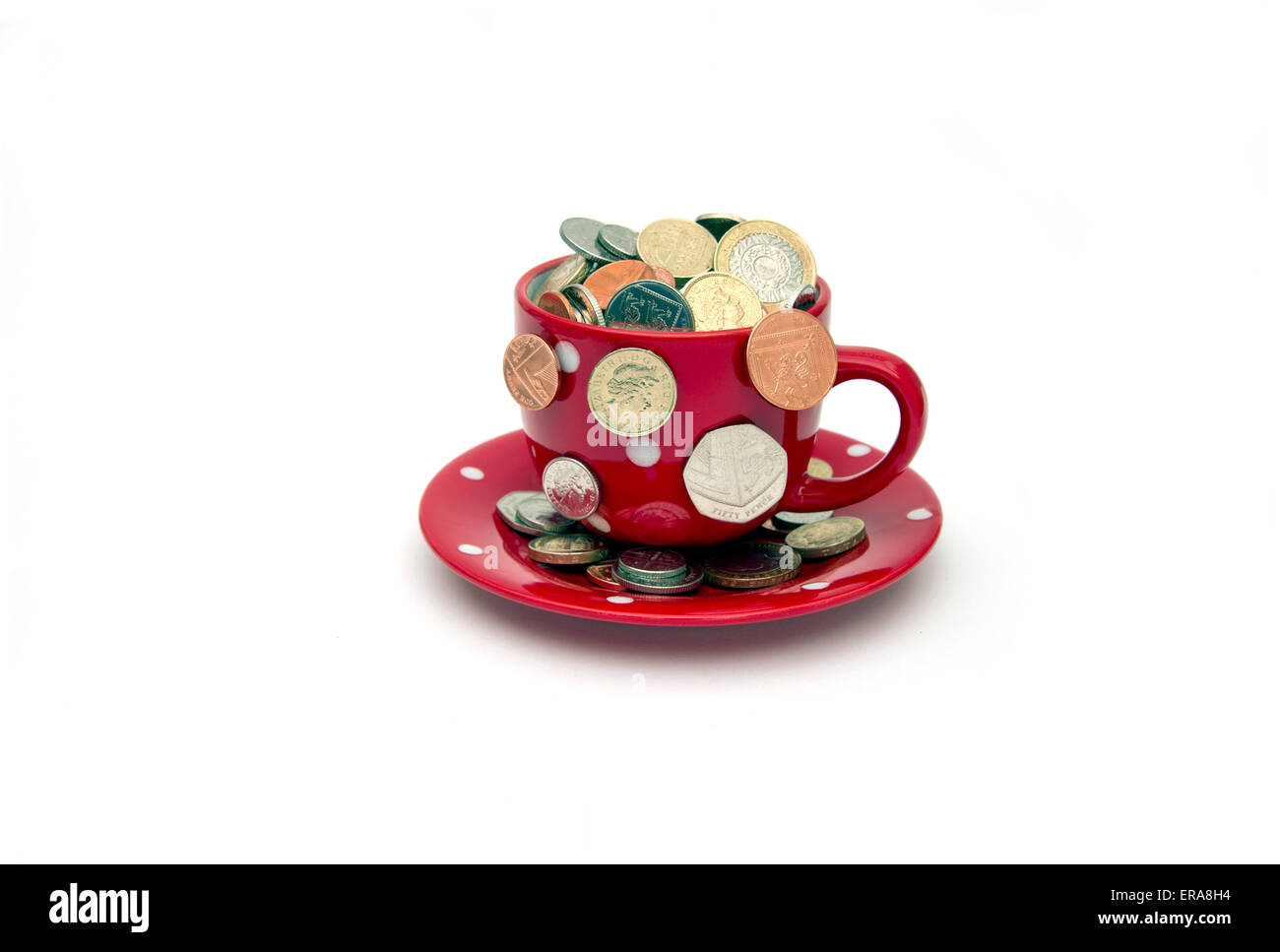 'My cup corre su un bicchiere di bianco e il piattino pieno di GBP British monete fuoriuscita.Un REGNO UNITO denaro economia finanza monete ricchezza Foto Stock