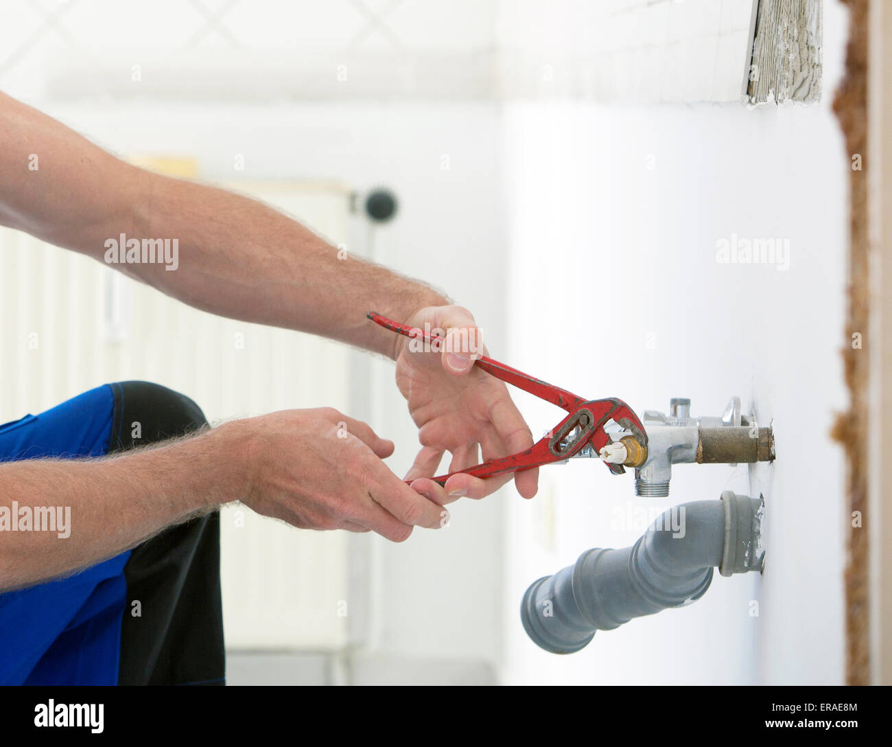 Close-up di plumber le mani lavorando su una tubazione con una chiave Foto Stock