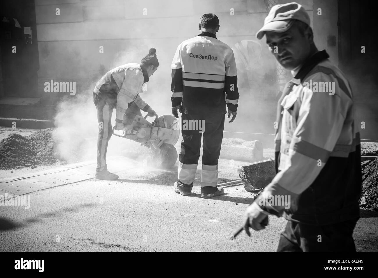 San Pietroburgo, Russia - 23 Maggio 2015: uomini al lavoro, strada urbana in costruzione, segagione di frontiera stradale pietre, nero e Foto Stock