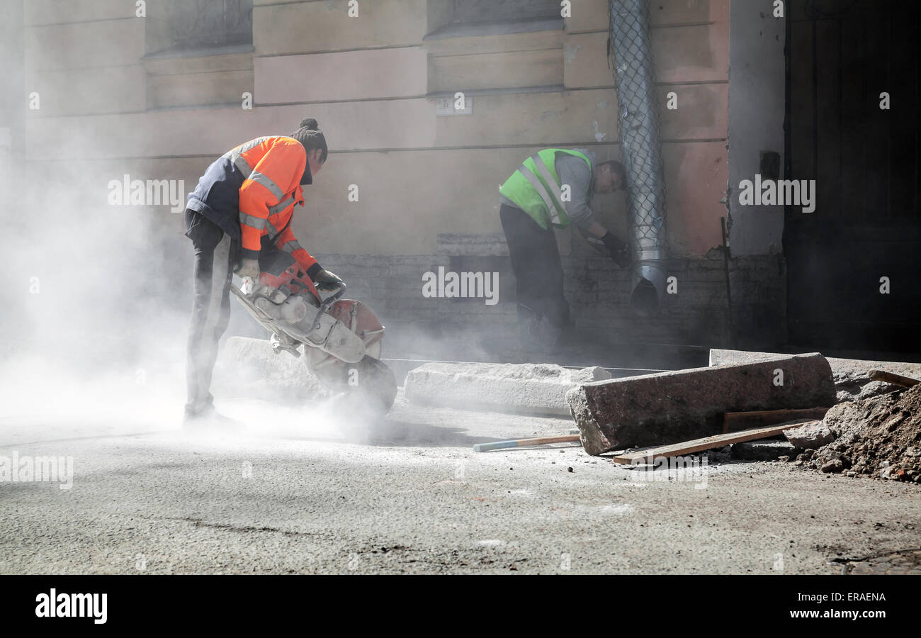 San Pietroburgo, Russia - 23 Maggio 2015: uomini al lavoro, strada urbana in costruzione, segagione di frontiera stradale Pietre Foto Stock