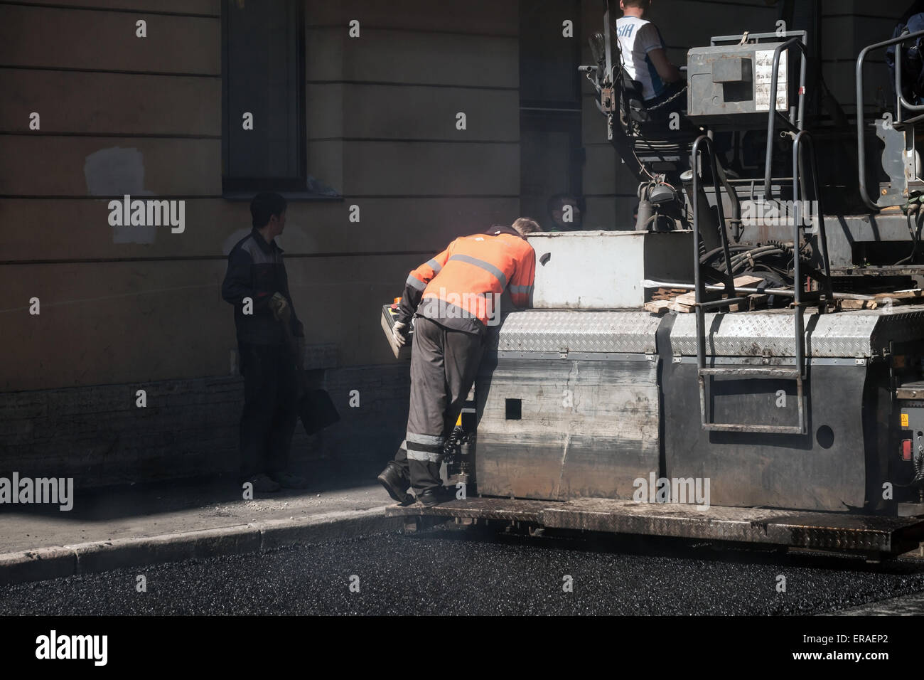 San Pietroburgo, Russia - 30 Maggio 2015: uomini al lavoro, strada urbana in costruzione, operatore lavora su lastricatore macchina Foto Stock