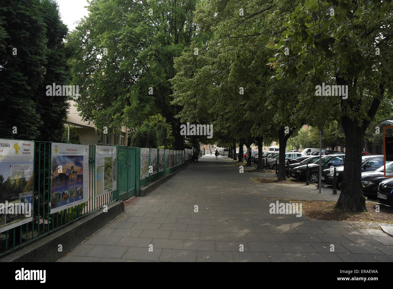 Vista lungo la pavimentazione stradale con alberi, automobili parcheggiate, cartelloni recinzione metallica, alla persona distanti a piedi, Dluga Street, Varsavia Foto Stock