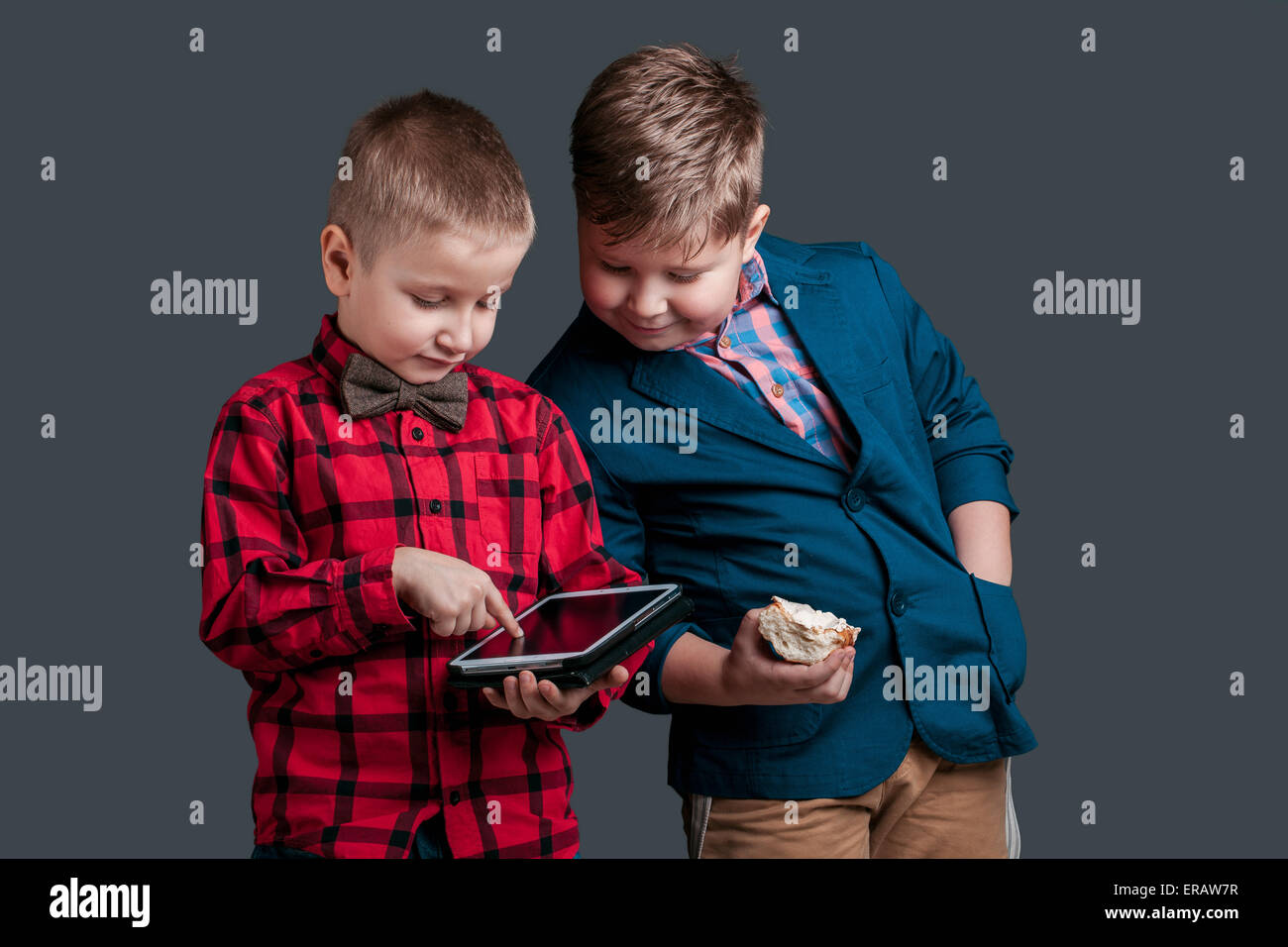Due ragazzi piccoli proprietari con la compressa isolata su uno sfondo scuro Foto Stock