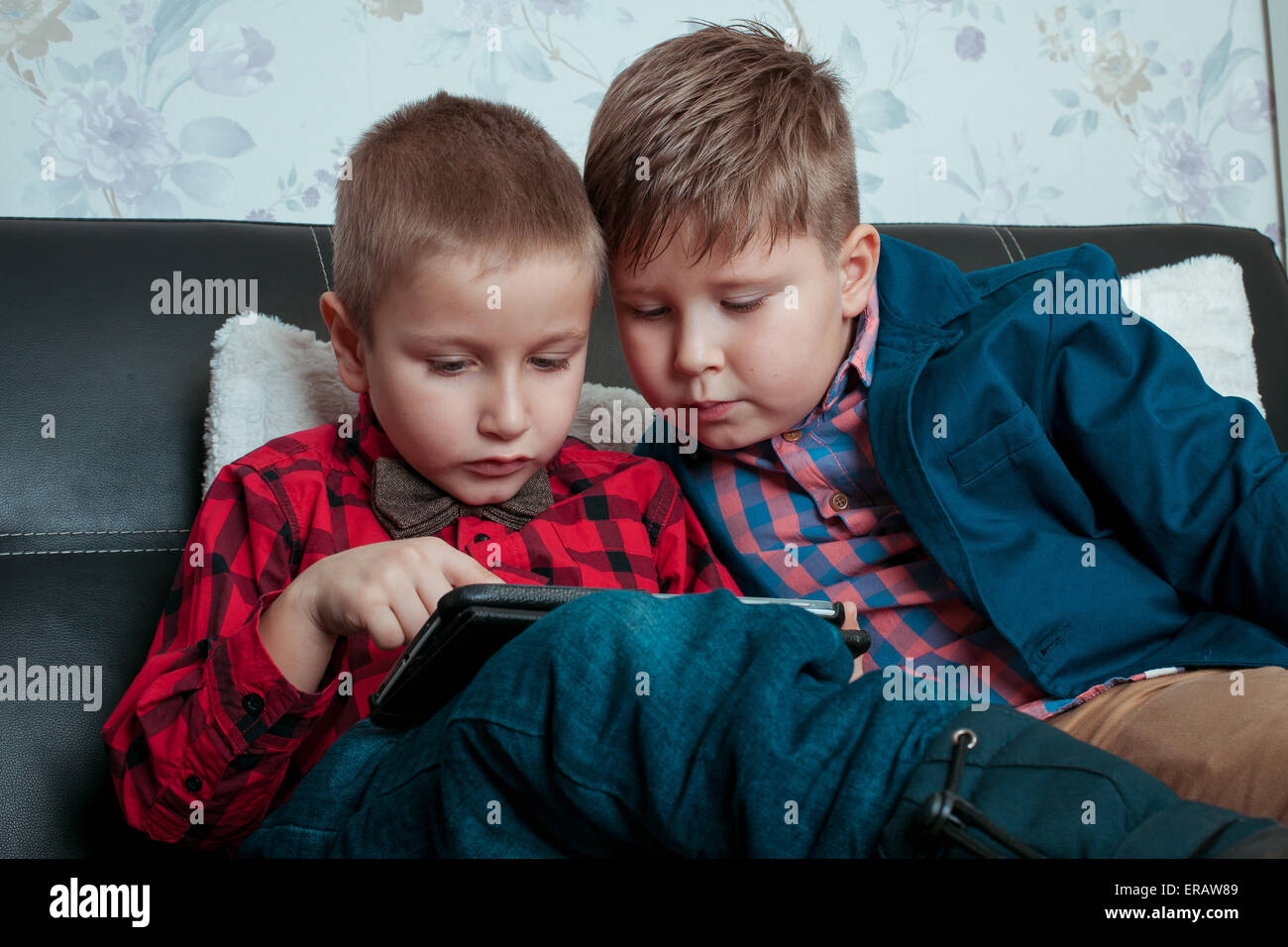 Due ragazzi piccoli proprietari con la compressa isolata su uno sfondo scuro Foto Stock