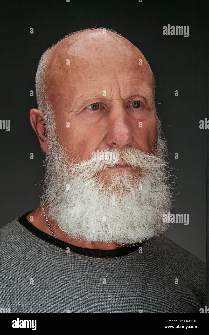 Uomo vecchio con una lunga barba con un grande sorriso su sfondo scuro Foto Stock