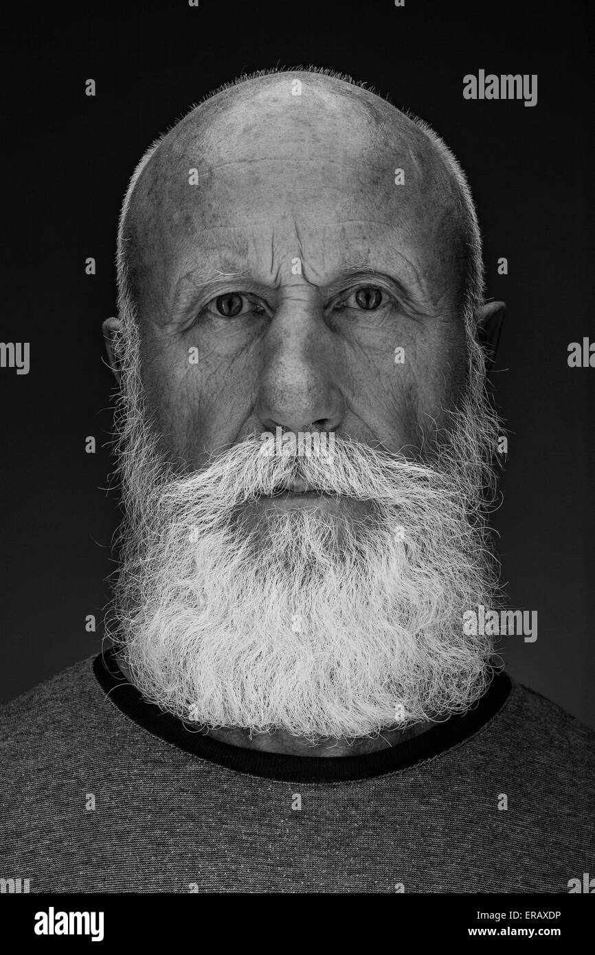 Uomo vecchio con una lunga barba con un grande sorriso su sfondo scuro Foto Stock