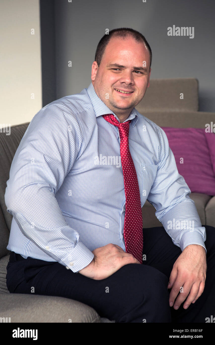 Uomo in camicia e cravatta si siede sul lettino e sorrisi Foto Stock