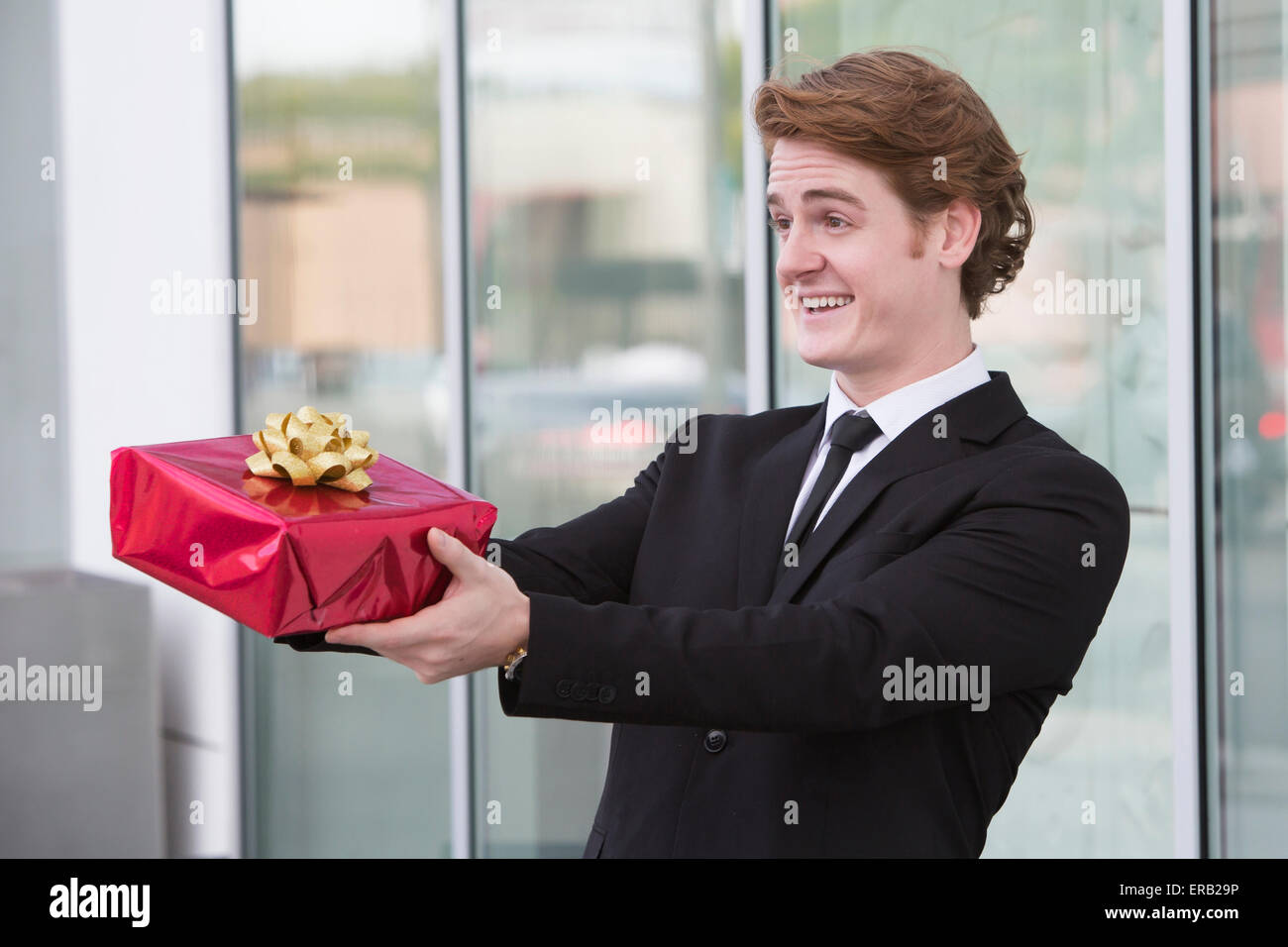 Uomo in tuta tenendo un dono nelle sue mani e sorrisi Foto Stock