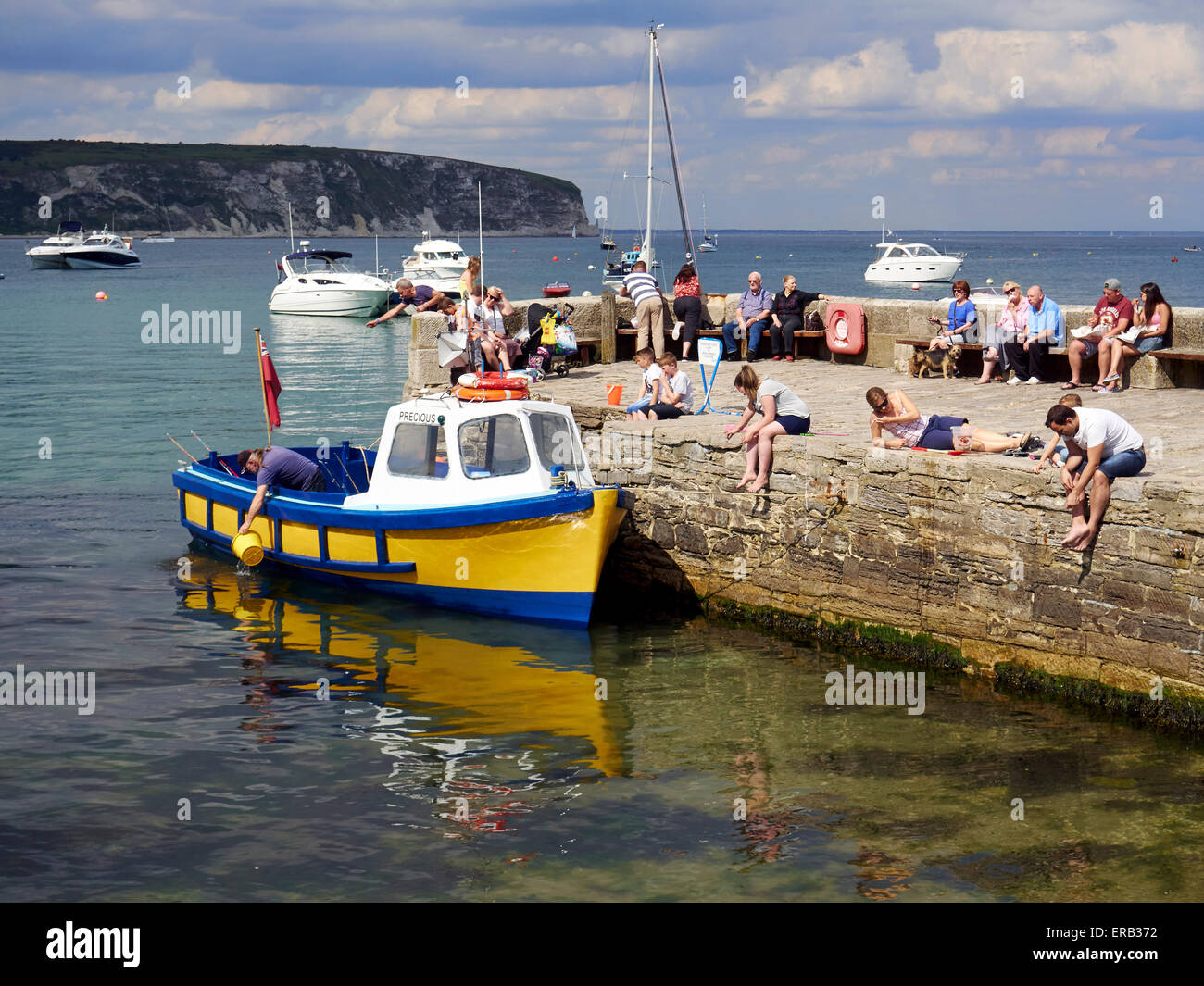Bambini e adulti pescato granchi dal molo di pietra di fronte al mare a Swanage, Dorset durante un weekend di festa. Foto Stock